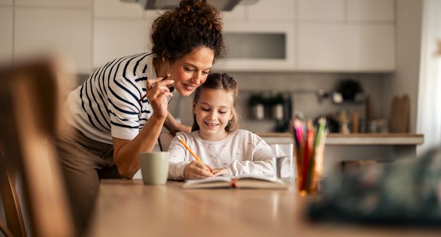 A,Mother,Helps,Her,Young,Daughter,Complete,Homework,In,A