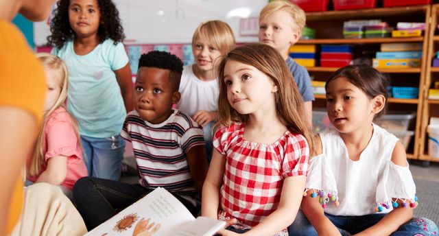 Group,Of,Elementary,School,Pupils,Sitting,On,Floor,Listening,To